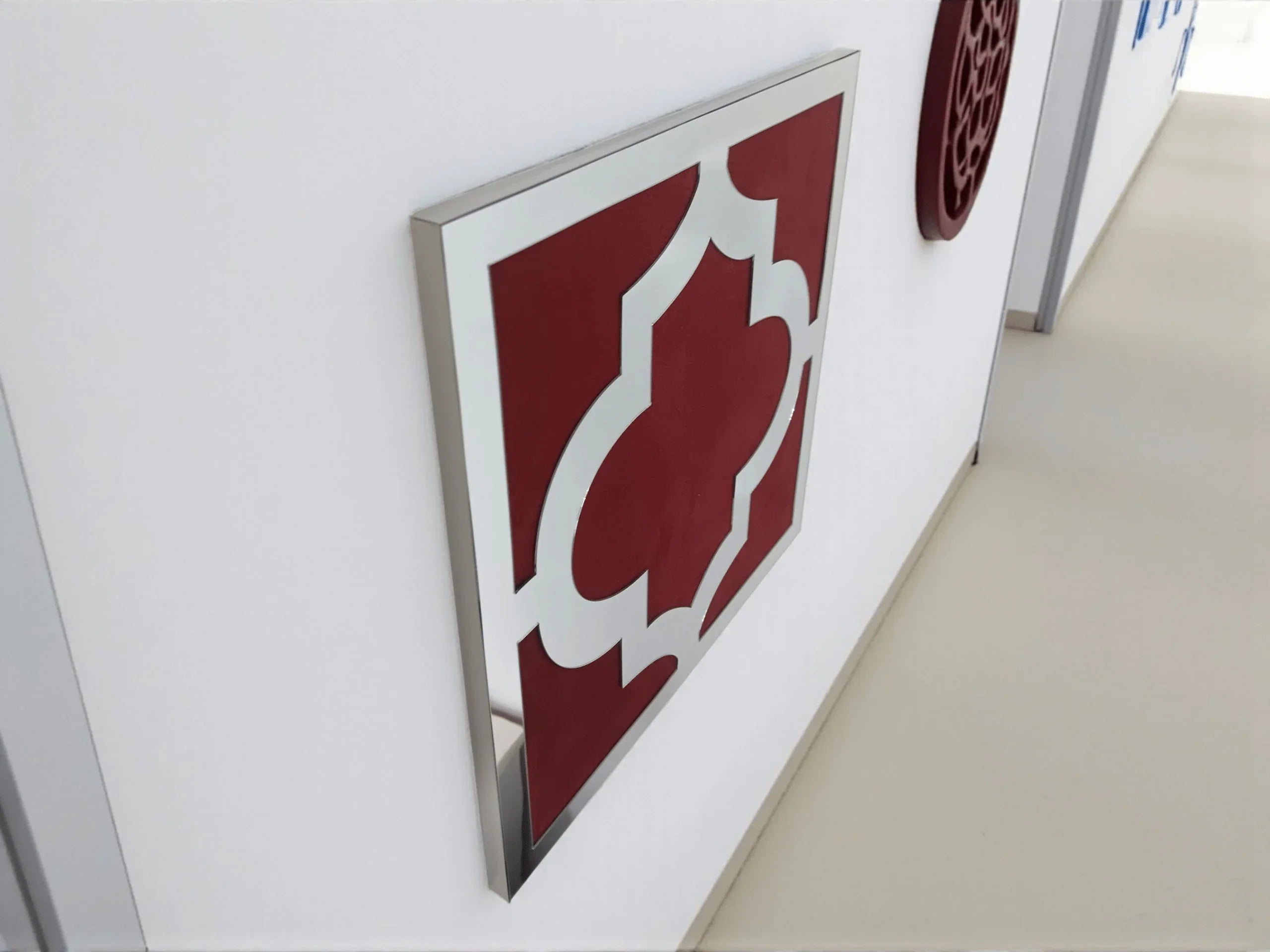 Décoration murale géométrique rouge et blanche dans un couloir moderne aux murs blancs