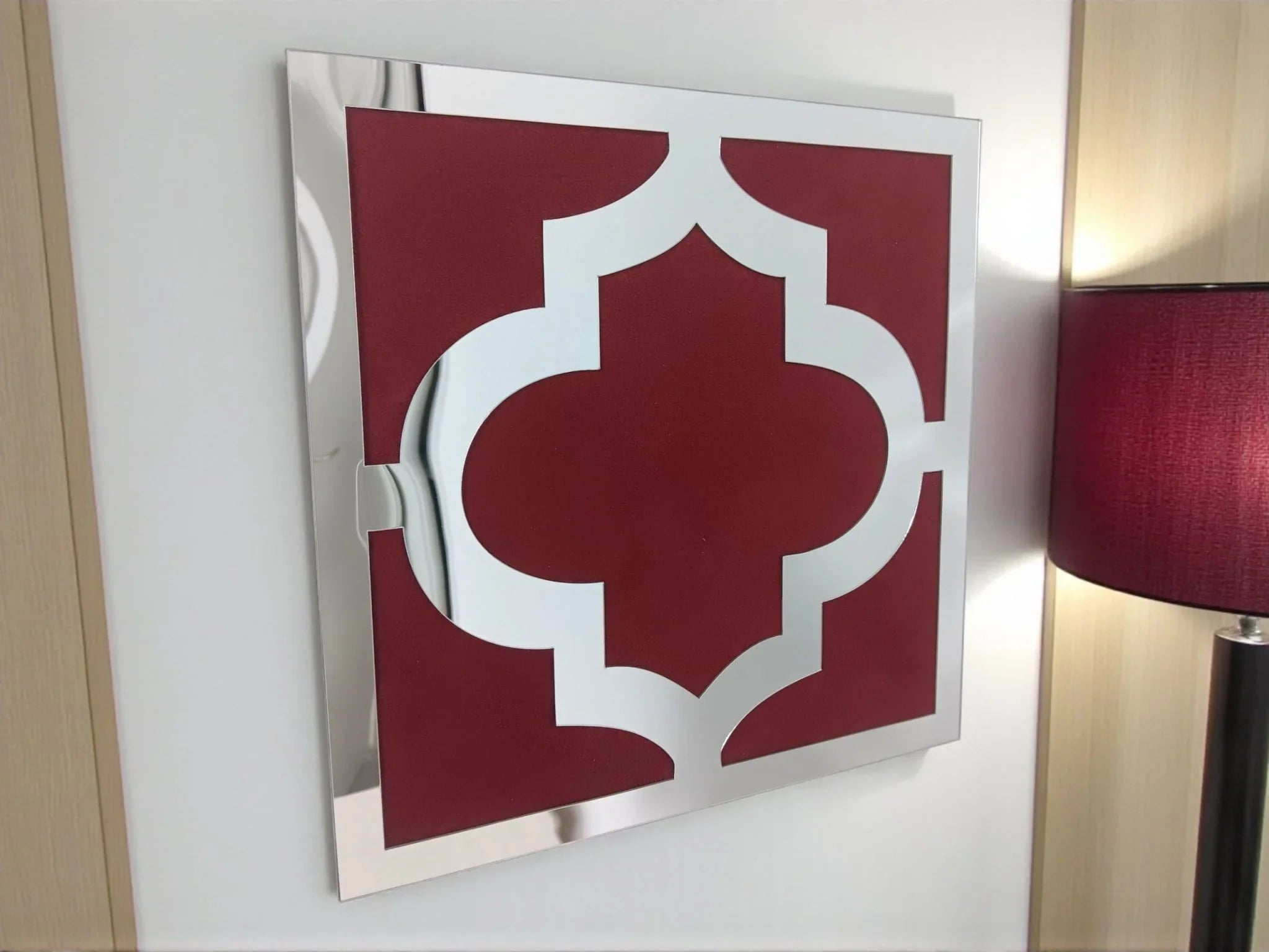 Décoration murale orientale en miroir acrylique argenté avec motif rouge bordeaux, lampe décorative à côté